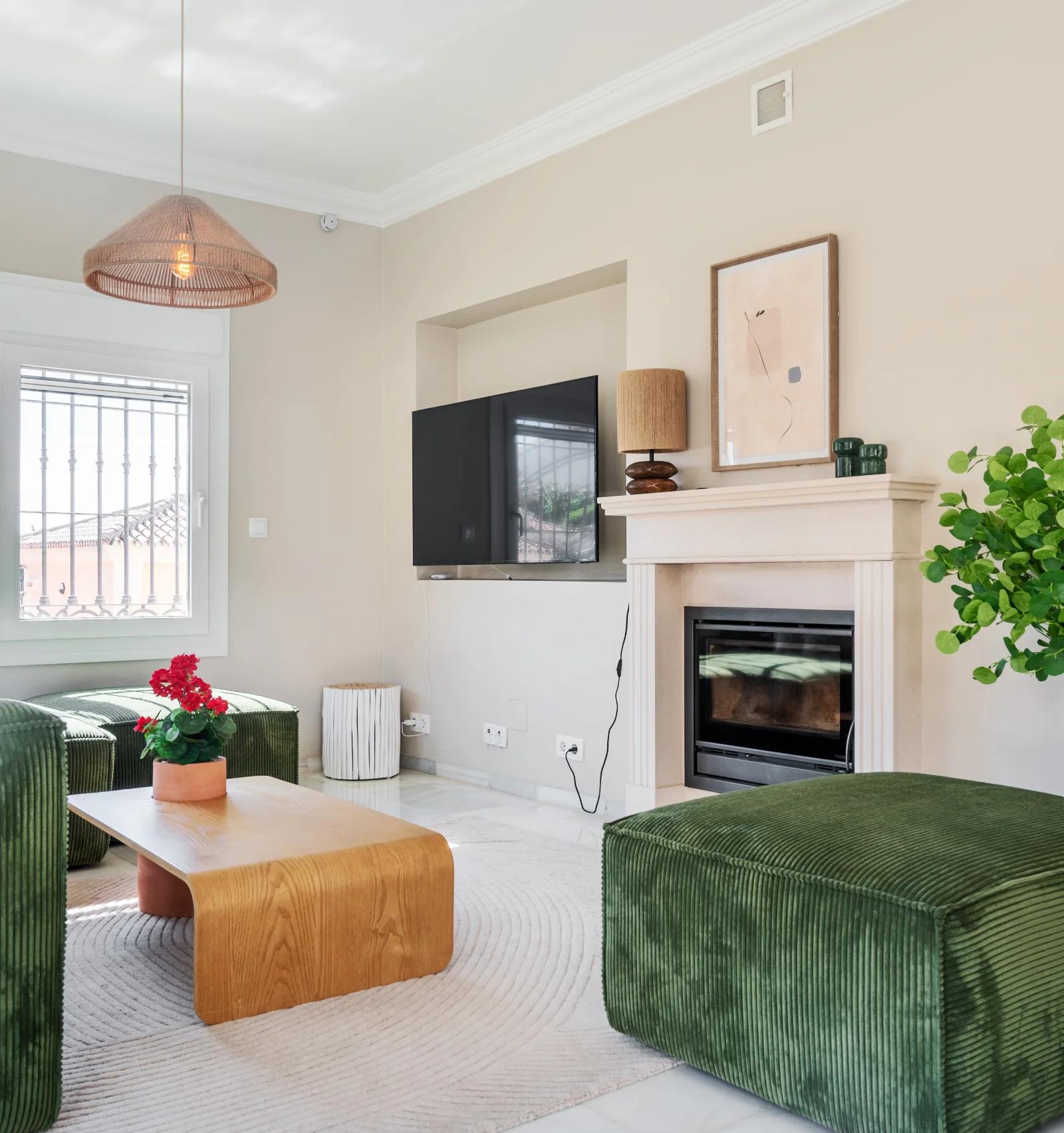 The living room, with a corduroy sofa facing the white marble fireplace and the television above it