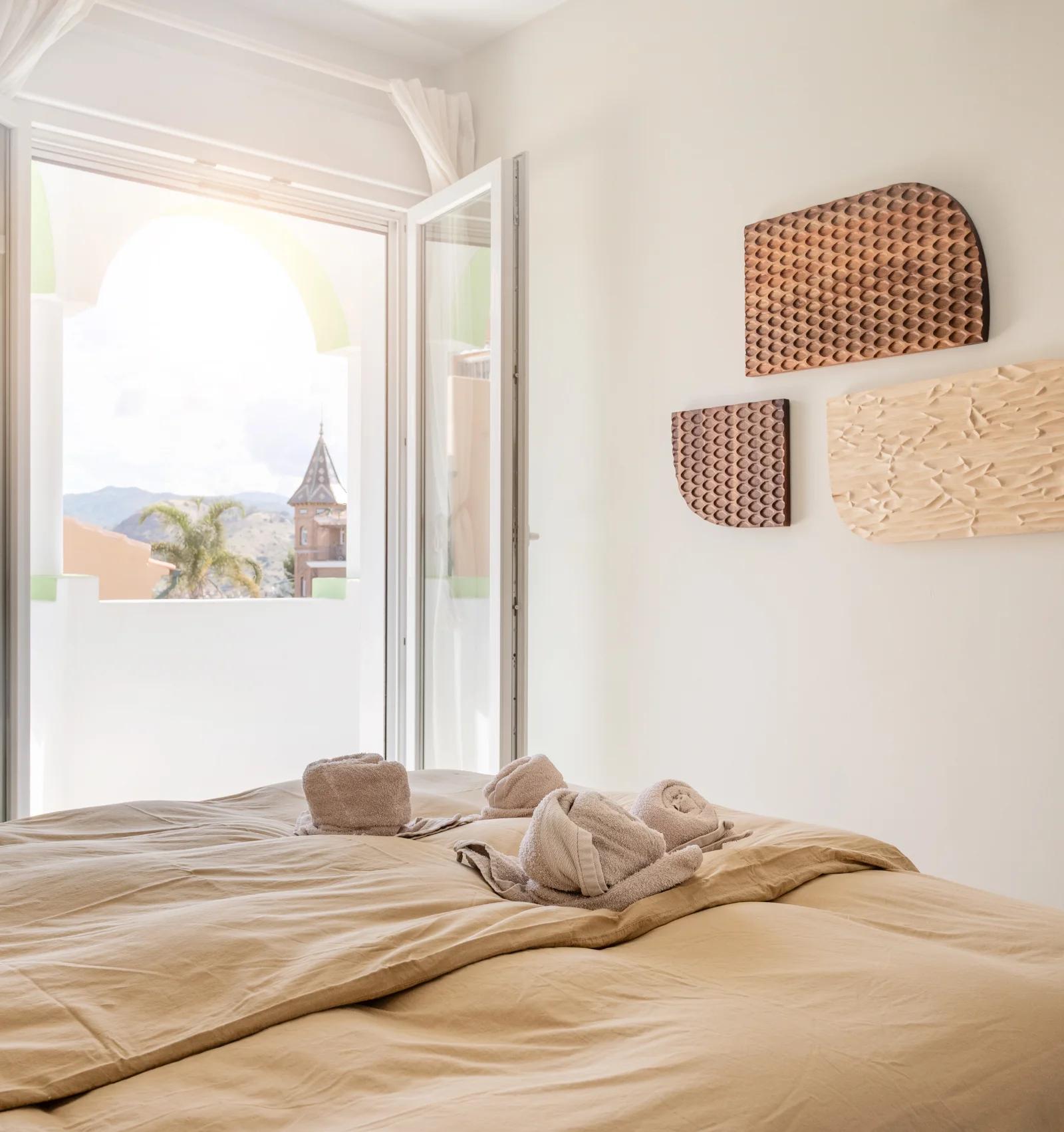 French doors open from the bedroom onto the terrace, with woven wall pieces beside the bed