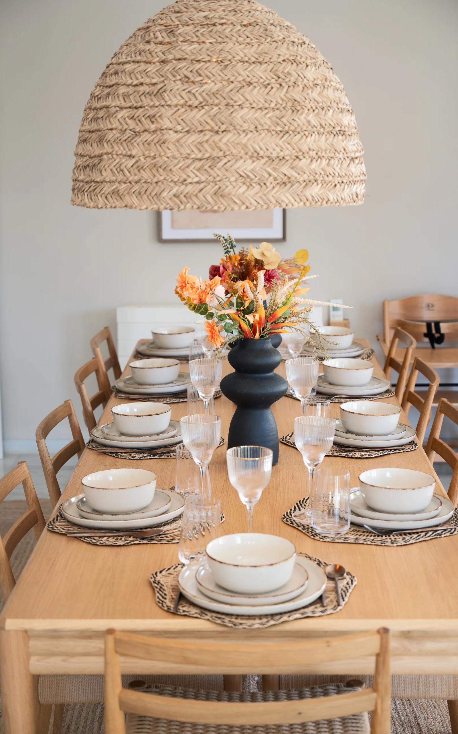 The dining table laid for a full house, with flowers in the middle and a high chair at the end
