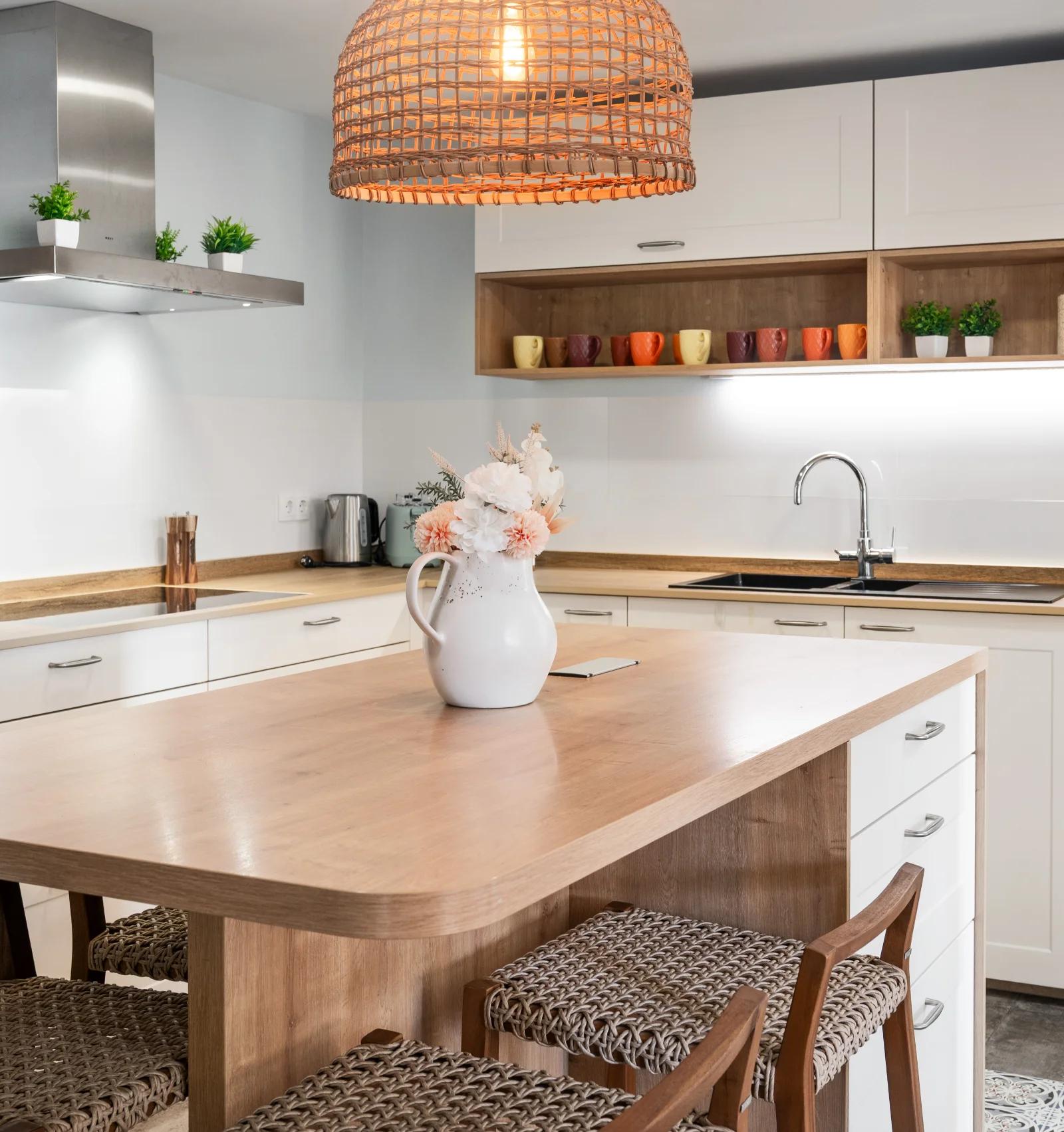 The kitchen island and bar stools, with cream cabinets, a wood worktop and the ovens behind
