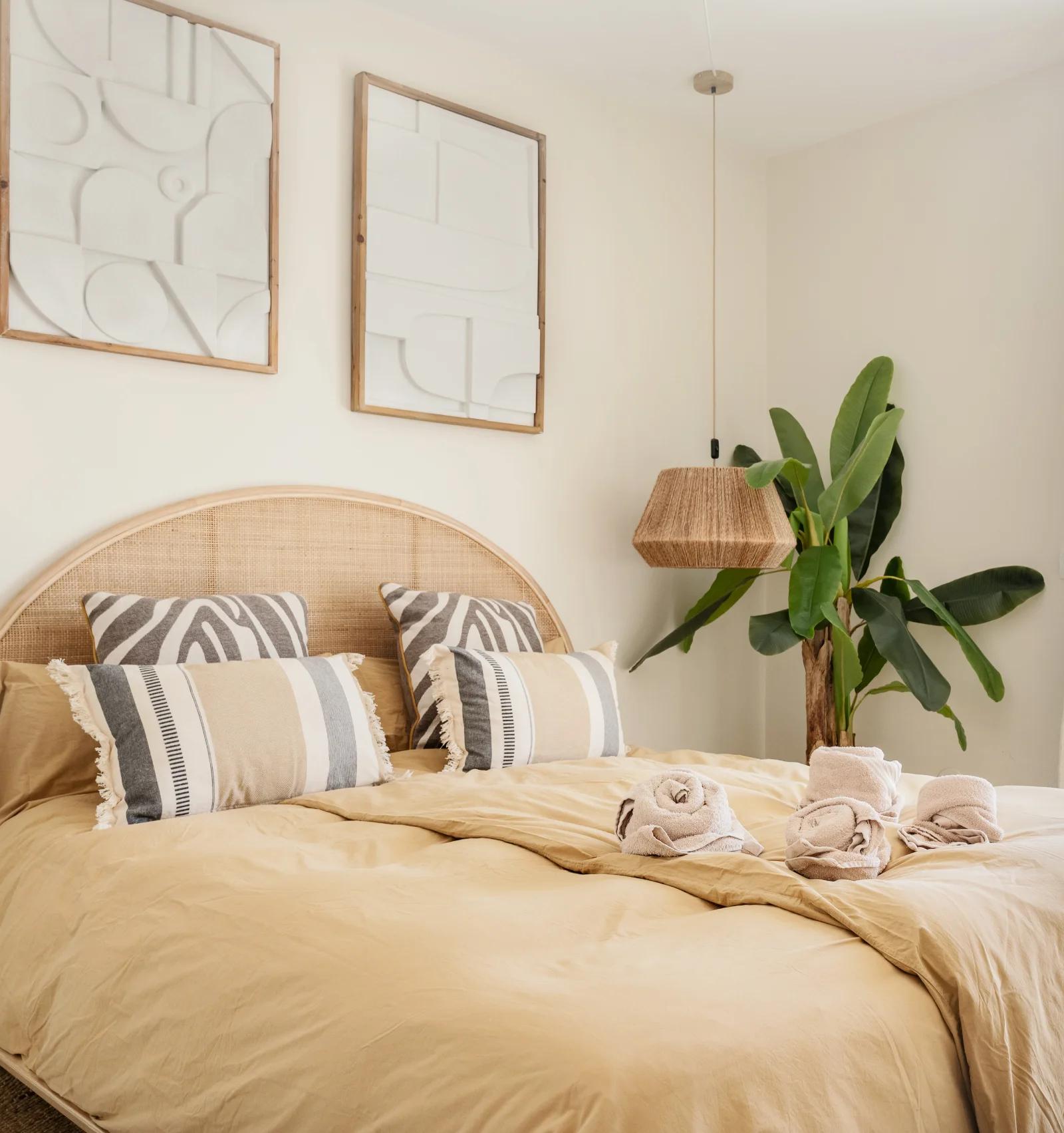 A bedroom with framed abstract prints above the bed and a door out to the terrace