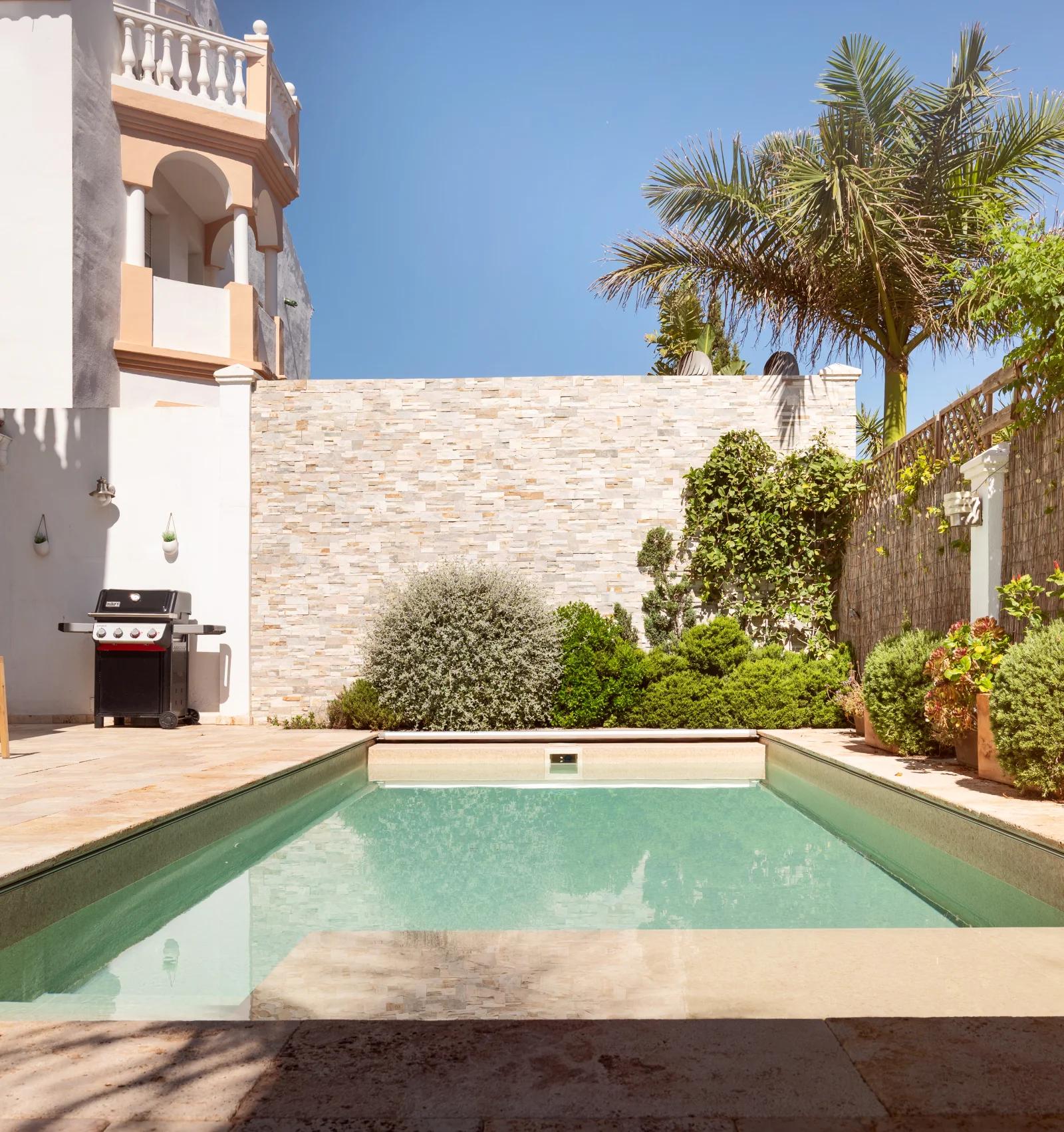 The pool in its walled courtyard, with the barbecue and planting along the far side