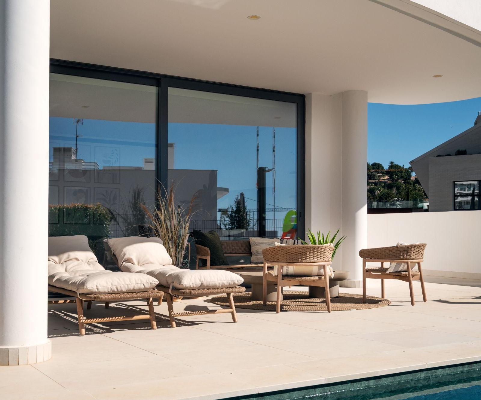 Covered outdoor lounge with rattan seating beside the pool